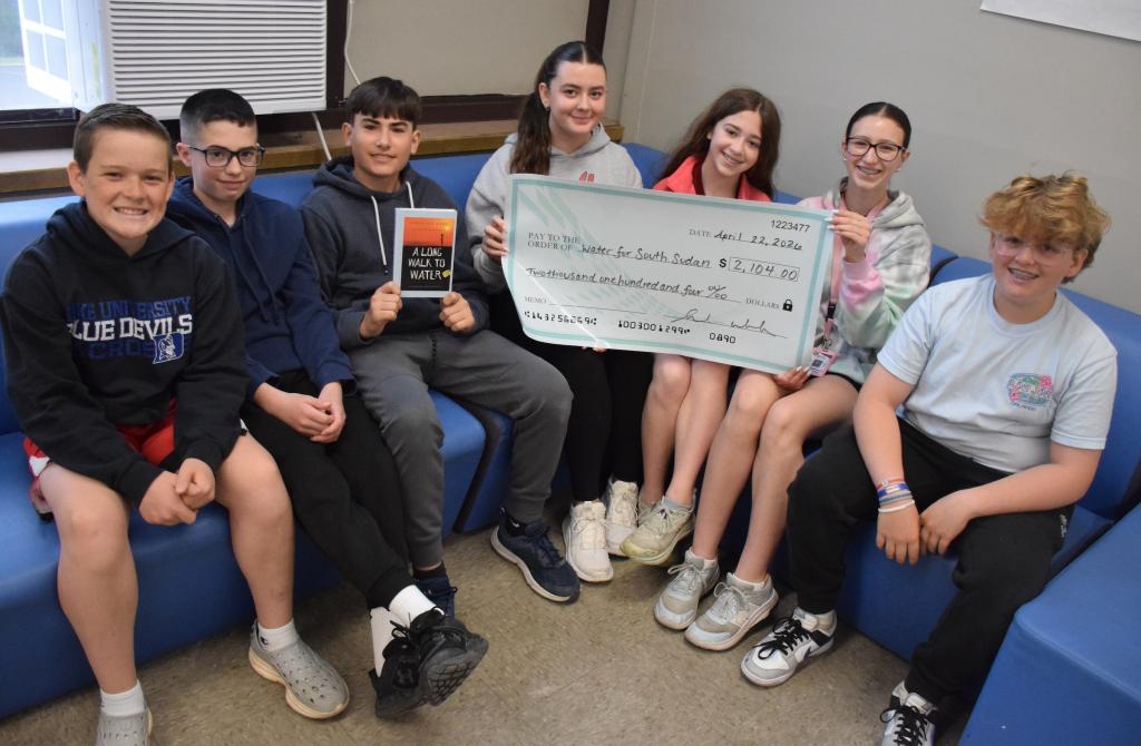 7 students sitting with one holding large check